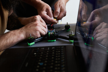 Close up of man's hands assembling a drone from parts, using tools, Preparing high-speed racing quadcopter for flight. Repair drone before training process.