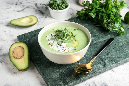 Bowl with green gazpacho and ingredients on grunge background