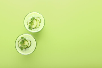 Glasses with green gazpacho on color background