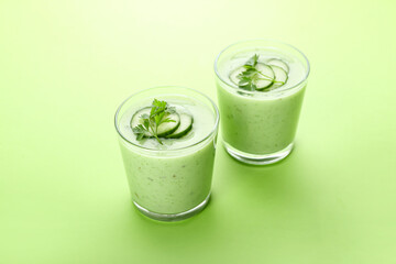 Glasses with green gazpacho on color background