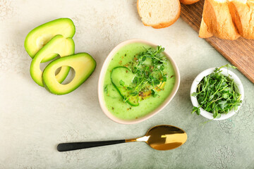 Bowl with green gazpacho and ingredients on color background