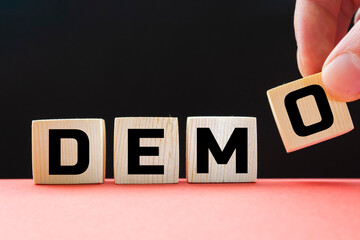 Demo symbol. Concept word 'demo' on cubes on a beautiful dark wooden background. Businessman hand....