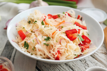 Plate with tasty sauerkraut on light wooden background