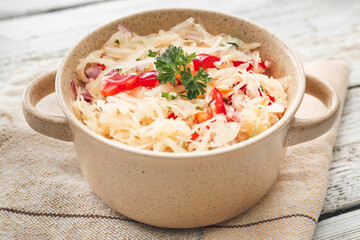 Pot with tasty sauerkraut on light wooden background