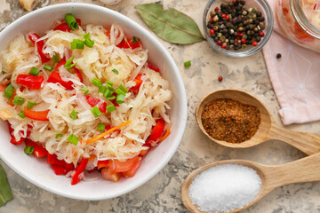 Bowl with tasty sauerkraut and ingredients on grunge background