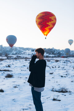 Tourist standing near flying hot air balloons flying up in cloud