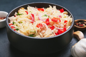 Bowl with tasty sauerkraut on dark background