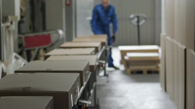 Post warehouse. Parcels move along a conveyor belt in the post-sorting department. Loading belt, postal worker prepares parcels for shipment. Online order delivery.