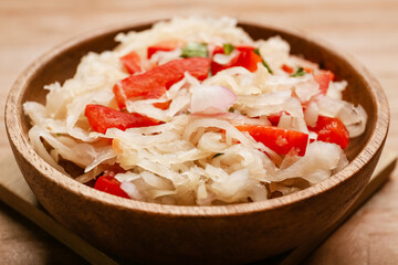 Bowl with tasty sauerkraut on wooden background, closeup
