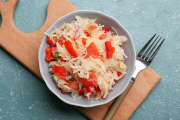 Plate with tasty sauerkraut on color background
