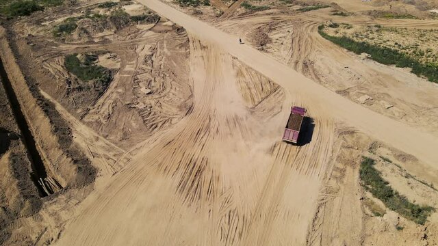 Dump truck transported sand from the open pit. Truck with tipper semi trailer working in quarry. Arial view of the opencast mine. Sand and gravel is excavated from ground. Mining industry.