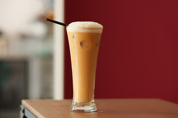 Glass of tasty iced coffee with milk on table