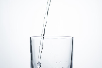 Jet of water or alcohol is pouring into a glass with splashes and bubbles, copy space