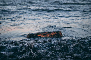 The wave has covered a log, something is floating in the sea, dirty water 