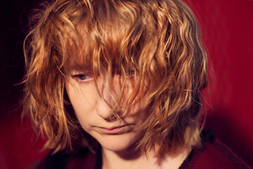 Fototapeta premium Portrait of serious sad tousled disheveled middle-aged woman on red background. Unprofessional female model in the Studio