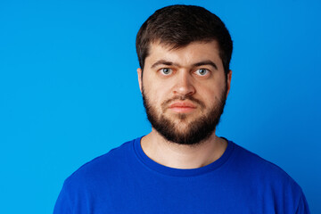 Fototapeta premium Close up portrait of caucasian bearded man on blue background