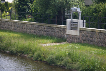 Modern flood protection wall in the style of the historic city wall. Permanent measures against floods. Dikes, gate valves, gates and walls. 
Flood gates protecting city against flooding from stream.