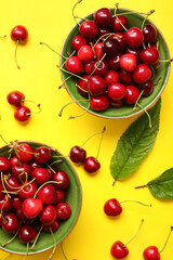 Fototapeta na wymiar Bowls with tasty ripe cherry on color background