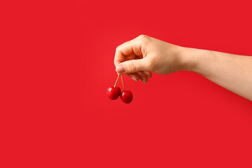 Woman holding tasty ripe cherry on color background - Powered by Adobe