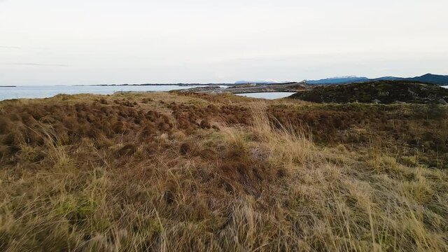 Dry Beach Grass At The Coastline Revealed Atlantic Ocean Road In Atlanterhavsveien, Norway. - Low Aerial Shot