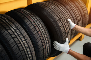 Close to the hands of a tire changer in Large warehouse of car tires, rack with customer car tires...