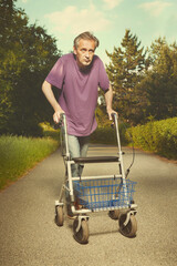 Older man on city sidewalk with his four wheel rollator walker