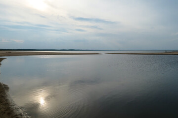 Fototapeta premium The coastal line of a sandy beach by the Baltic Sea on Sobieszewo island, Poland. The sea is gently waving. A bit of overcast. Solitude and serenity