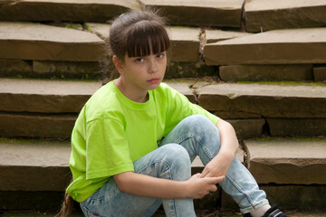 Sad child. The sad little girl (eight years old) sits on the old steps. Looking into the camera....