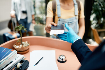 Close-up of tourist checking in at hotel reception during COVID-19 pandemic.