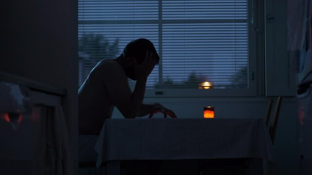 sad crying man recieves message of bad news in dark home at night