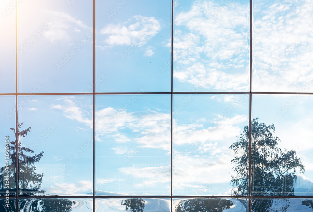 Poster sky, clouds and tree reflection in grid of glass window of modern building. nature and environment v