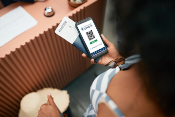 Close-up of female guest using digital coronavirus vaccination passport while checking in a hotel.