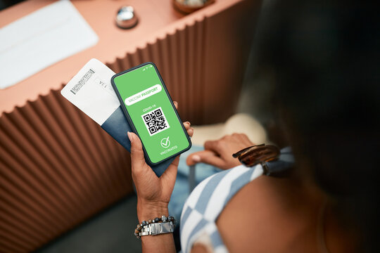 Close-up of vaccinated woman with COVID-19 health certificate on smart phone during checking in at hotel reception.