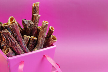 Dried dental goodies for dogs on a pink background.