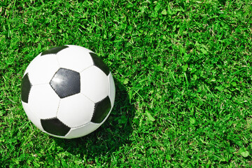 Fototapeta na wymiar Top view on classic soccer ball on bright green grass on football field. Summer playing sports. Copy space.