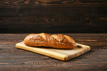 Fresh wheat bread on wooden cutting board