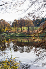 Autumn leaves are reflected in the water of the Windach reservoir in Bavaria