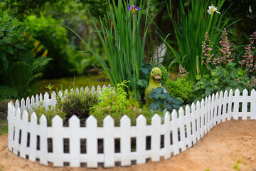 Landscape design in home garden. View of landscaped area with plants in yard or backyard. Small white hedge and  garden figurine of a duck. 