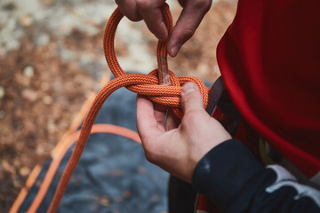 man holding a rope and preparing to climb the mountains. Rock climbing equipment in detail close up photo.
