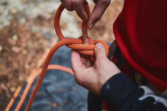 man holding a rope and preparing to climb the mountains. Rock climbing equipment in detail close up photo.