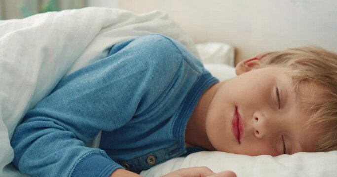 Close up of little caucasian boy sleeping sweetly in bed in morning. Concept of healthy baby sleep.