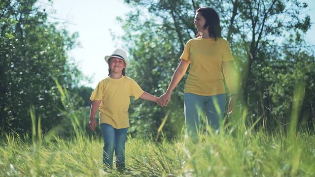 Happy family. Mom and daughter in forest park. People walk on grass. Happy team mom and daughter. Family is walk on grass in park. People walk along the tava in forest. Happy family concept