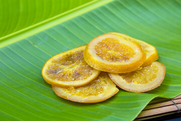 Preserved sliced dried oranges on a green banana leaf close up macro citrus fruit omn natural green background