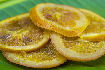 Preserved sliced dried oranges on a green banana leaf close up macro citrus fruit omn natural green background