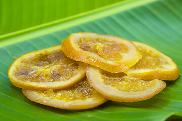 Preserved sliced dried oranges on a green banana leaf close up macro citrus fruit omn natural green background