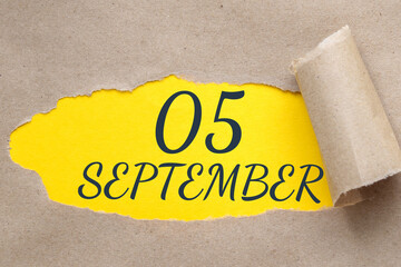 september 05. 05th day of the month, calendar date.Hole in paper with edges torn off. Yellow background is visible through ragged hole.Autumn month, day of the year concept