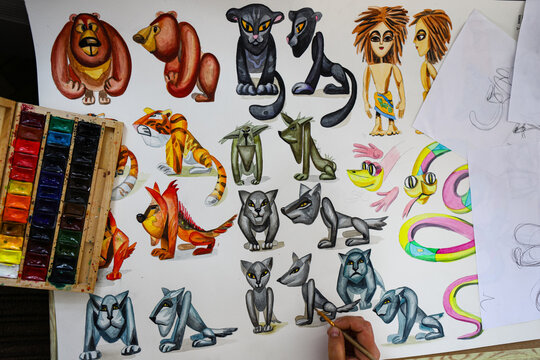 The animator draws with a pencil and draws characters from cartoons, comics or puppet shows. Mowgli's play. Preparing to make a doll. The designer creates sketches. Comics, cartoons, puppet theater