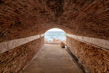 Beautiful stone tunnel with the beach at the end of it.