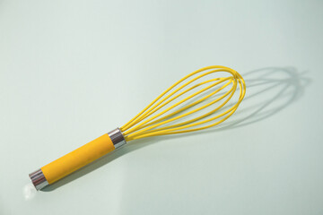 Yellow whisk isolated on mint background 