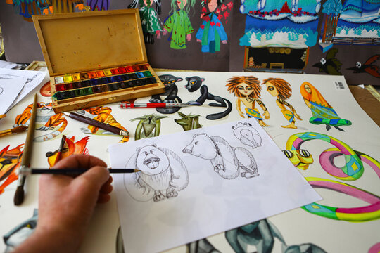 The animator draws with a pencil and draws characters from cartoons, comics or puppet shows. Mowgli's play. Preparing to make a doll. The designer creates sketches. Comics, cartoons, puppet theater